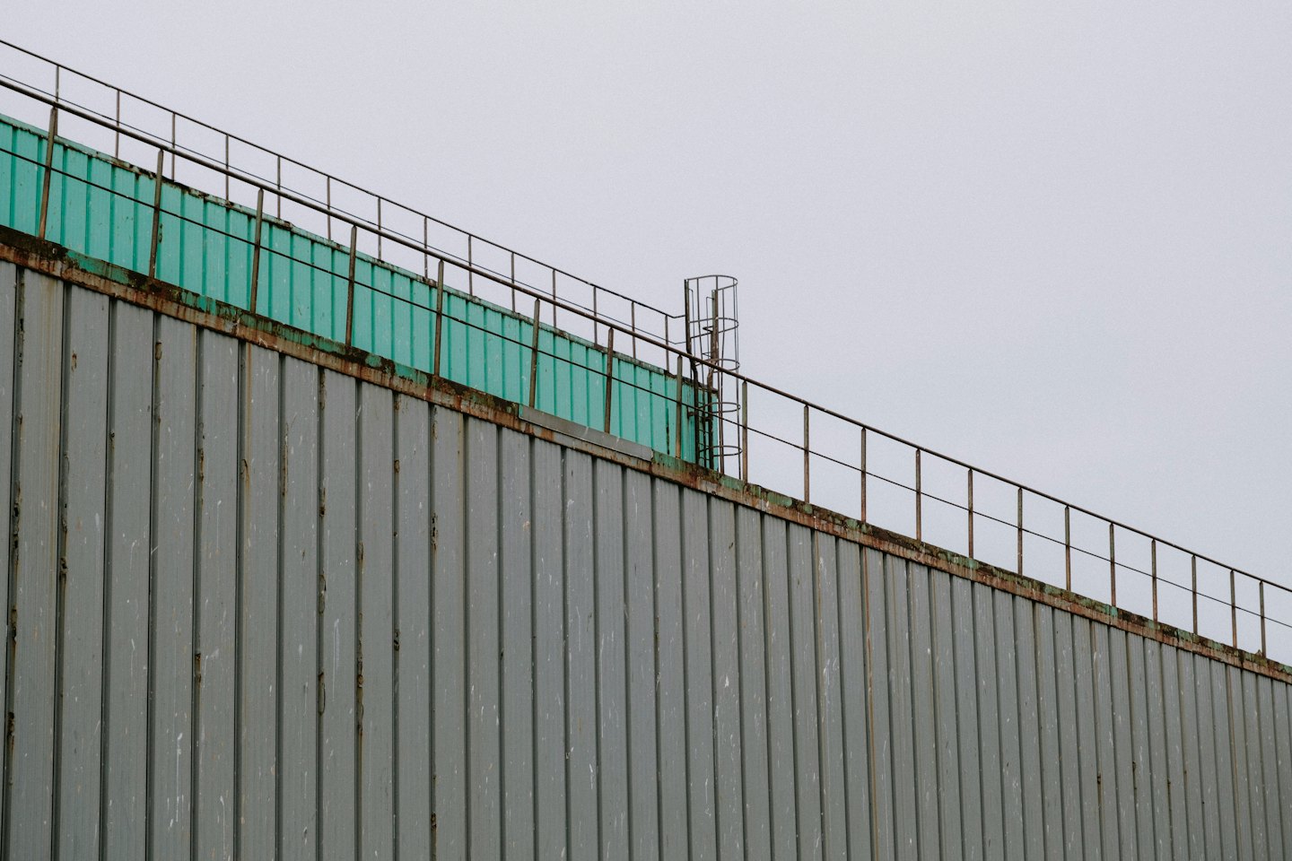 Rusty corrugated metal industrial building under an overcast sky.